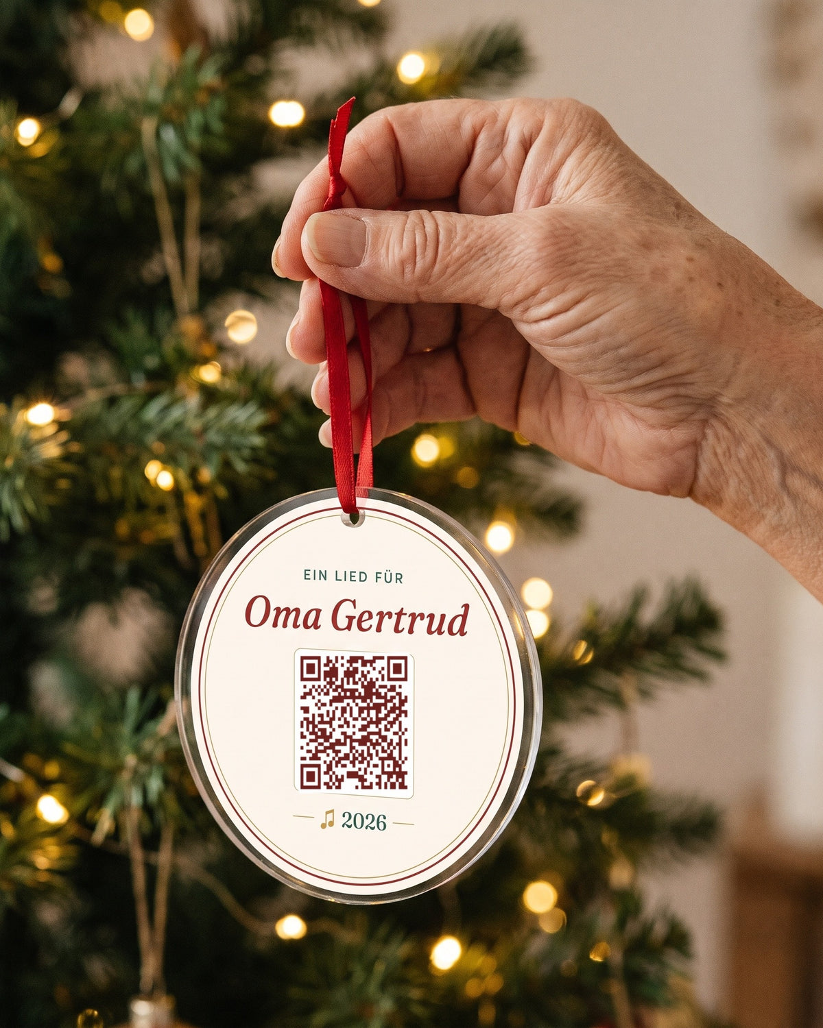 Hand hält den Christbaum-Anhänger mit rotem Band (Beispiel)