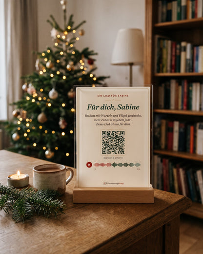Acryl-Aufsteller mit Songtitel, Refrain und QR-Code auf einem Sideboard vor dem Weihnachtsbaum (Beispiel, Name erfunden)