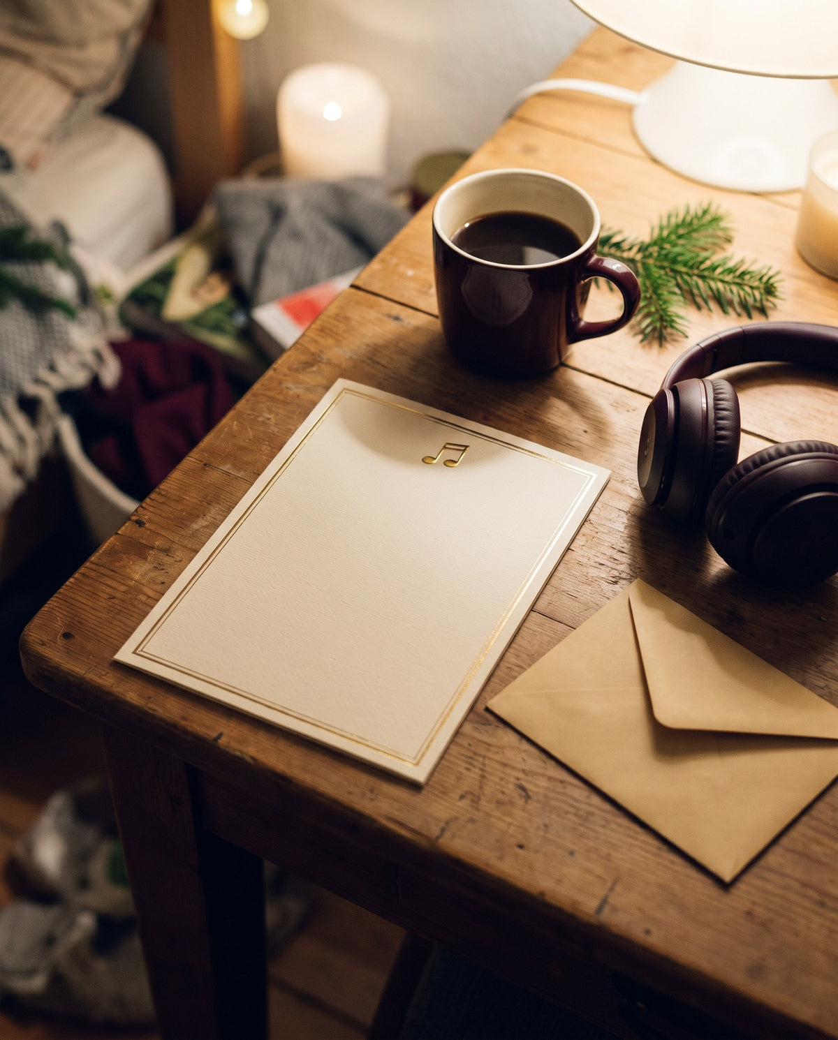 Gedruckte Songtext-Karte mit Goldrand auf einem Holztisch neben Kaffeetasse, Kopfhörern und Umschlag
